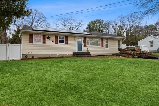 ranch-style house featuring entry steps, roof mounted solar panels, and a front yard