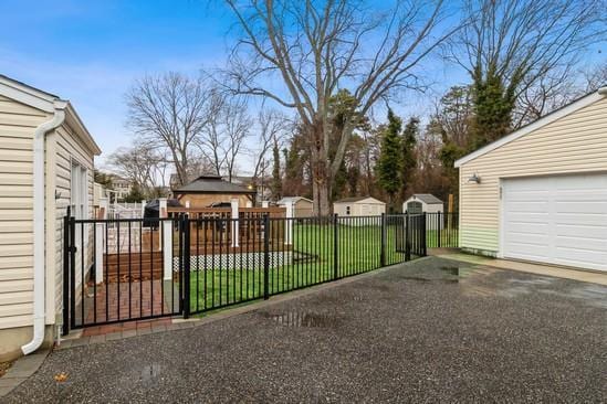 view of gate featuring a yard, an outdoor structure, and fence