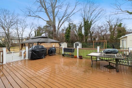 deck with outdoor dining space, an outdoor structure, area for grilling, and a shed