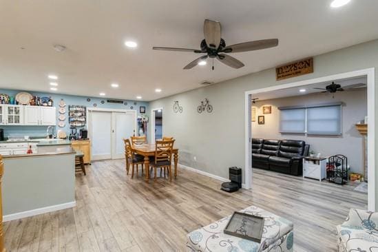 living area featuring baseboards, ceiling fan, recessed lighting, and light wood-style floors