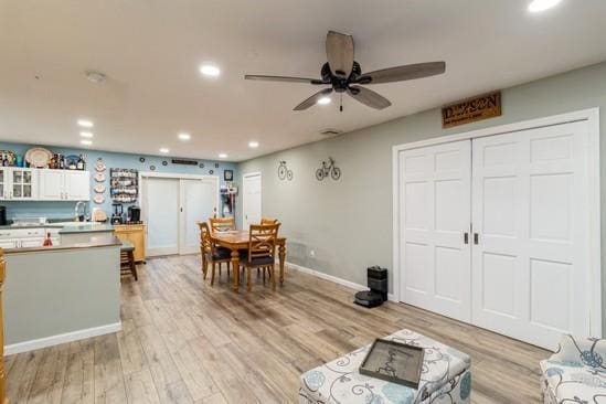 interior space with baseboards, light wood-type flooring, a ceiling fan, and recessed lighting