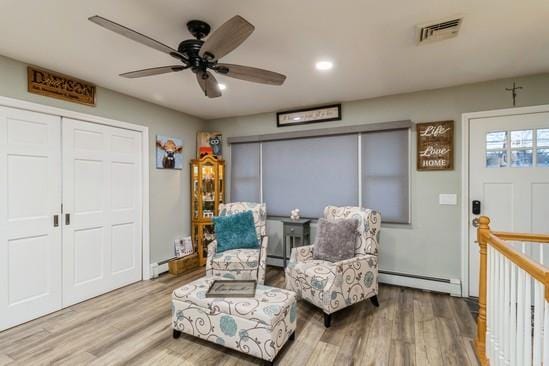 sitting room with recessed lighting, wood finished floors, an upstairs landing, visible vents, and baseboard heating