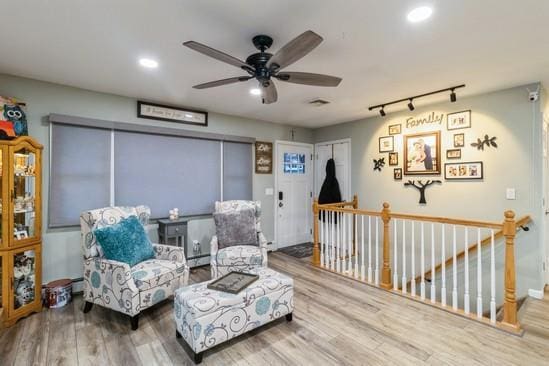 sitting room with wood finished floors, an upstairs landing, and recessed lighting