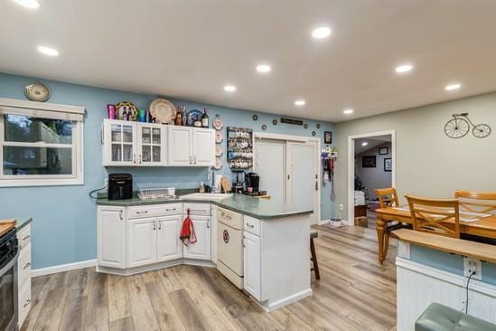 kitchen featuring white cabinets, dishwasher, a peninsula, and light wood finished floors