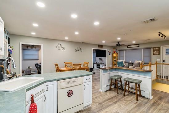 kitchen featuring white dishwasher, recessed lighting, a sink, visible vents, and light wood-type flooring