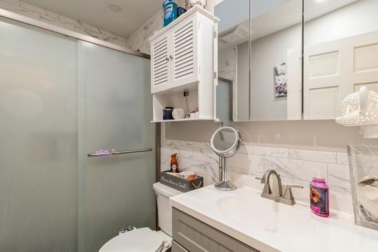 full bath featuring a stall shower, toilet, vanity, and decorative backsplash