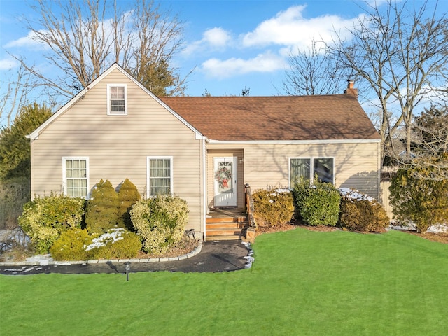 view of front of home with roof with shingles, a front lawn, and a chimney