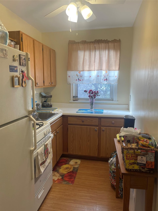 kitchen featuring white appliances, light wood-style flooring, brown cabinets, light countertops, and a sink