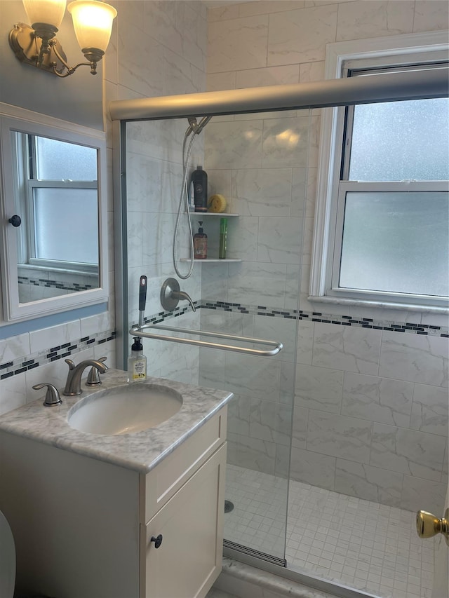 full bath featuring a shower stall, decorative backsplash, and vanity