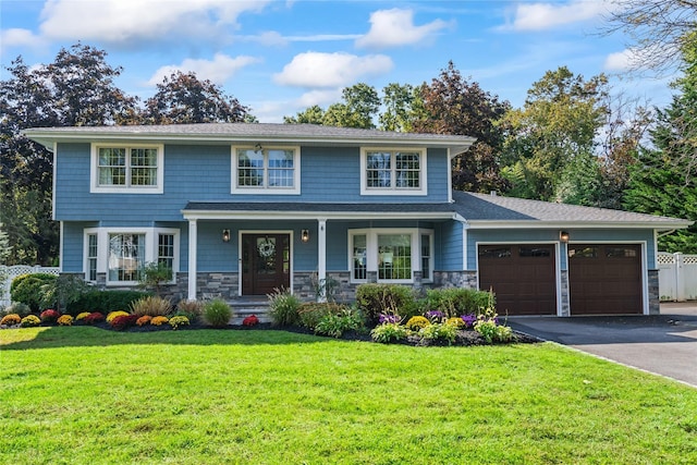 view of front of home featuring aphalt driveway, a front yard, fence, a garage, and stone siding