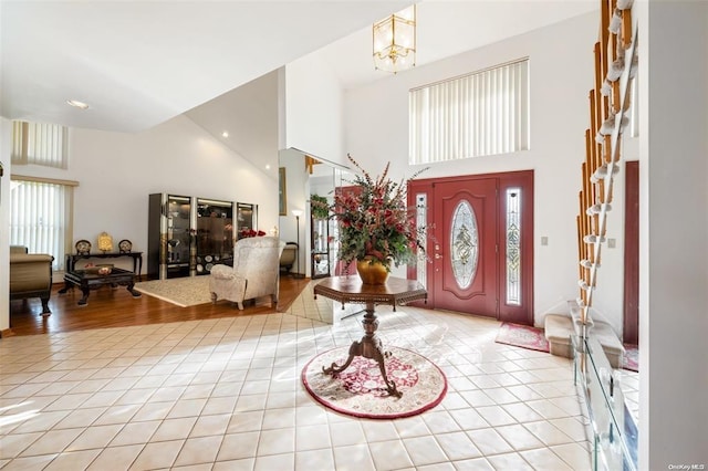 foyer with light tile patterned flooring, a towering ceiling, and an inviting chandelier