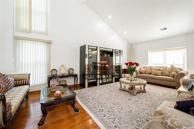 living area featuring visible vents, high vaulted ceiling, and wood finished floors