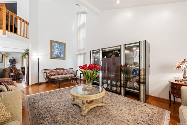 living room with wood finished floors, a towering ceiling, and baseboards