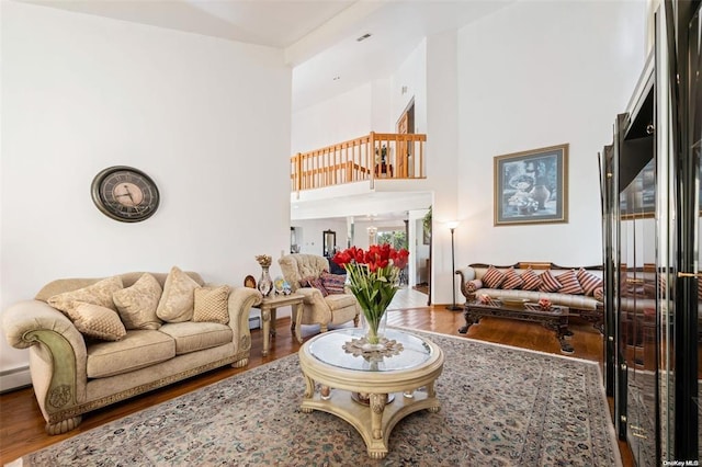 living area featuring wood finished floors and a towering ceiling