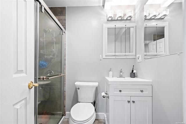 full bathroom with toilet, a stall shower, baseboards, and vanity