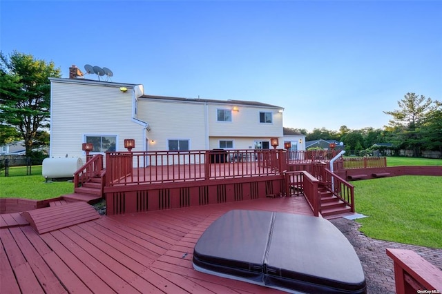 deck with a yard, fence, a covered hot tub, and heating fuel