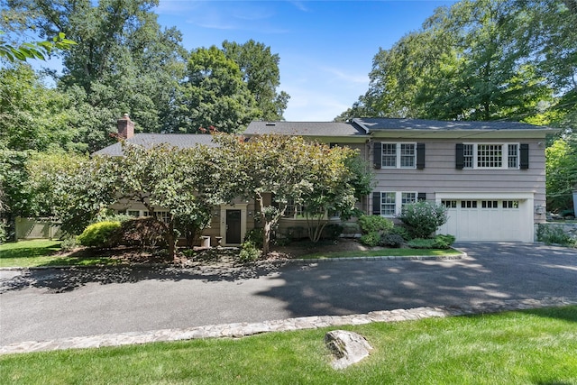 view of front of property with an attached garage, a chimney, and aphalt driveway