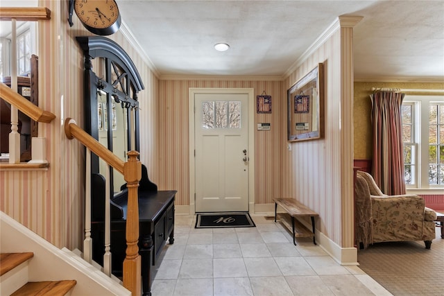 entrance foyer with light tile patterned floors, wallpapered walls, baseboards, ornamental molding, and stairs