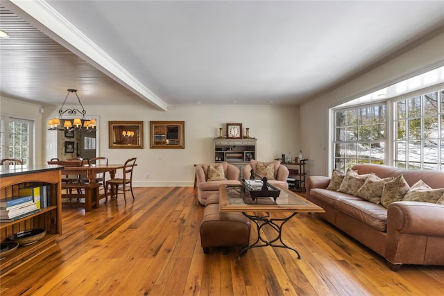 living room featuring baseboards, a notable chandelier, and light wood finished floors