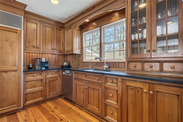 kitchen with dark countertops, brown cabinets, dishwasher, and a sink