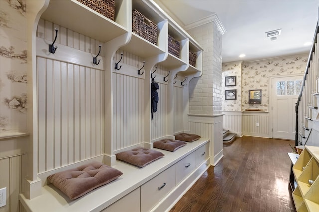 mudroom featuring a wainscoted wall, dark wood-style flooring, visible vents, ornamental molding, and wallpapered walls