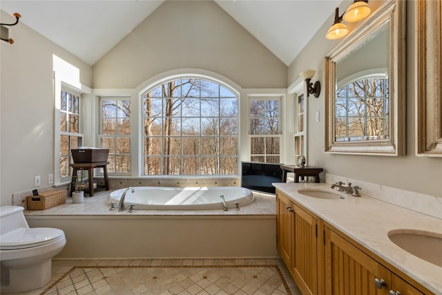 bathroom with double vanity, toilet, a sink, vaulted ceiling, and a bath