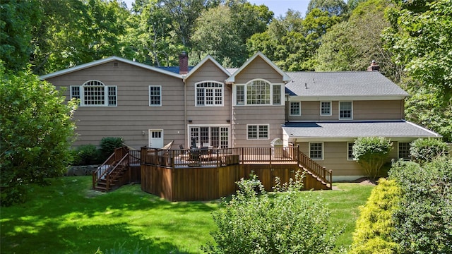 back of property with a deck, stairway, a chimney, and a lawn