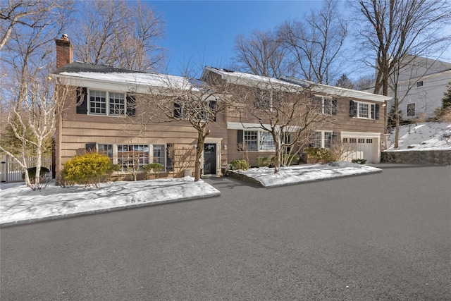 view of front of property with a garage, aphalt driveway, and a chimney