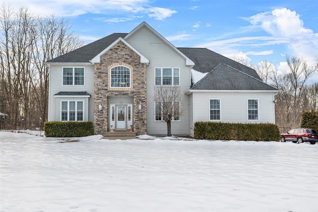 traditional home featuring stone siding and roof with shingles