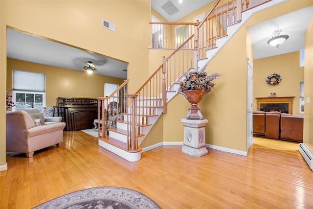 staircase featuring a lit fireplace, visible vents, and wood finished floors