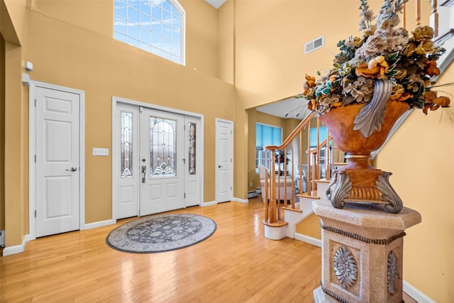 entrance foyer featuring stairs, visible vents, baseboards, and wood finished floors