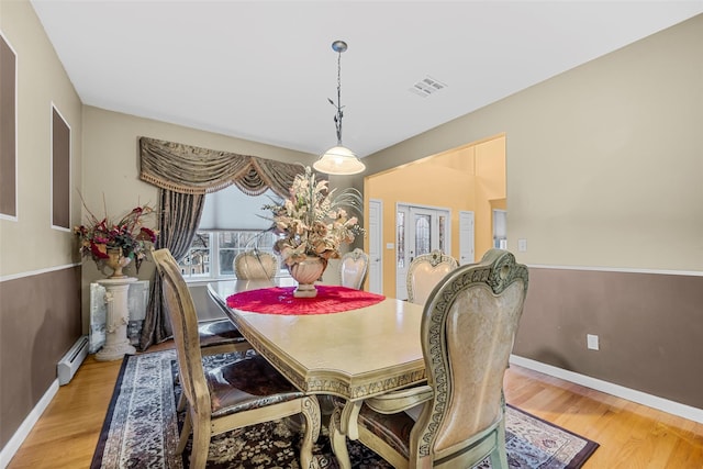 dining room with a baseboard radiator, light wood-style floors, visible vents, and baseboards