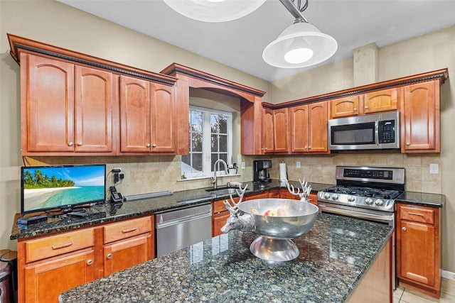 kitchen featuring hanging light fixtures, tasteful backsplash, appliances with stainless steel finishes, and a sink