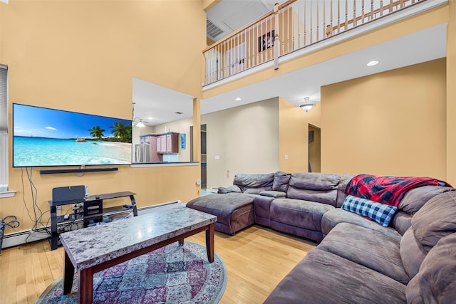 living area with a towering ceiling and wood finished floors