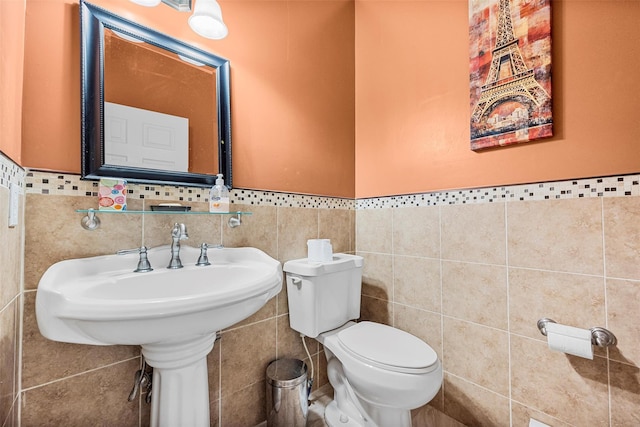 bathroom featuring wainscoting, toilet, and tile walls