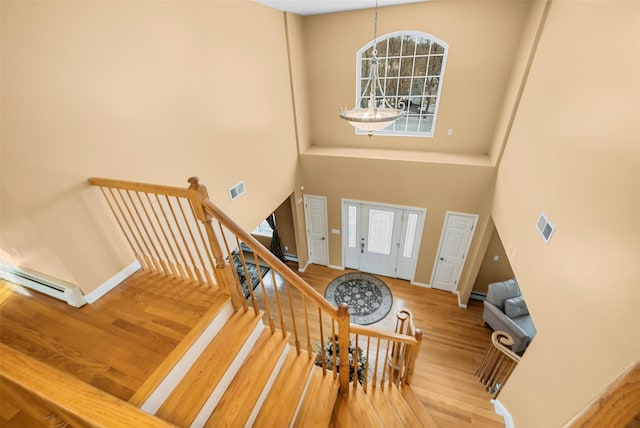 entrance foyer with visible vents, a towering ceiling, and wood finished floors