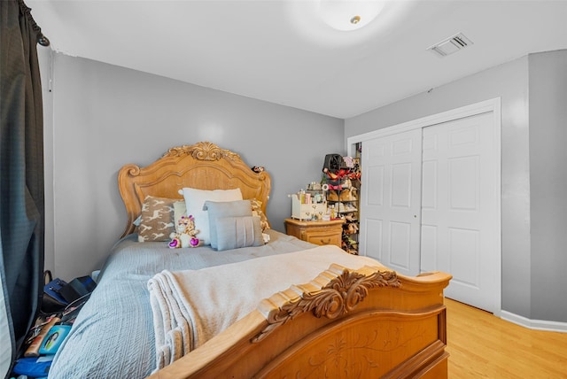 bedroom with a closet, visible vents, light wood-style flooring, and baseboards