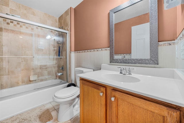 bathroom featuring tile walls, toilet, enclosed tub / shower combo, vanity, and tile patterned floors