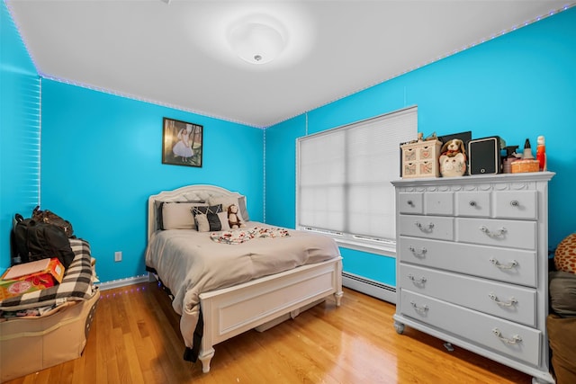 bedroom with light wood-style floors, a baseboard radiator, and baseboards