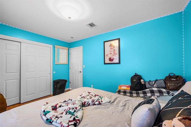 bedroom with a closet, visible vents, and wood finished floors