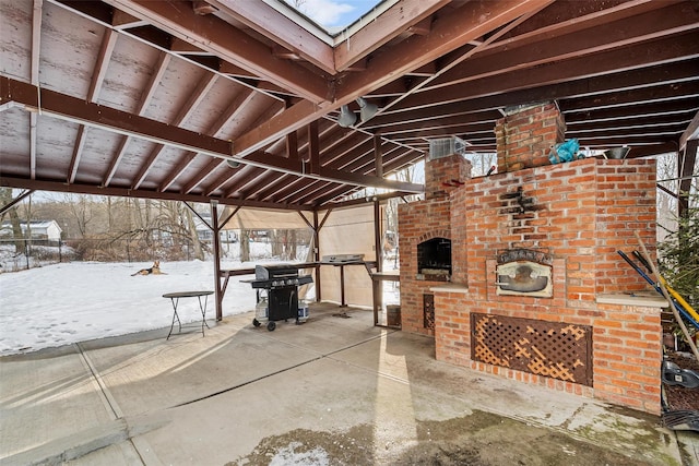 snow covered patio featuring grilling area and a fireplace