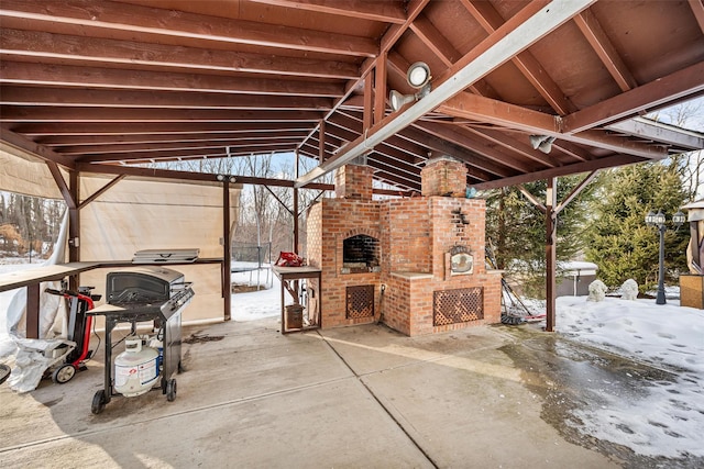 snow covered patio featuring exterior fireplace and grilling area