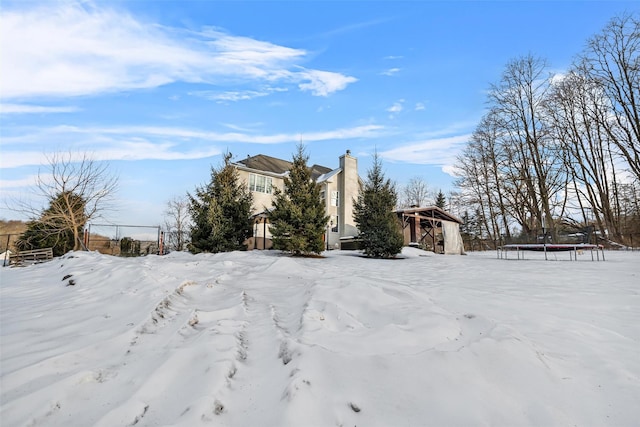 snowy yard with a trampoline, an outdoor structure, and a storage shed