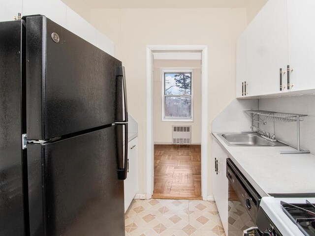 679 W 239th St Unit 1C, Bronx, NY 10463 - kitchen with black appliances, radiator, light countertops, and white cabinetry