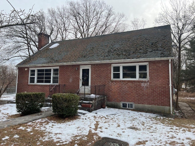 view of front facade featuring a shingled roof, brick siding, and a chimney