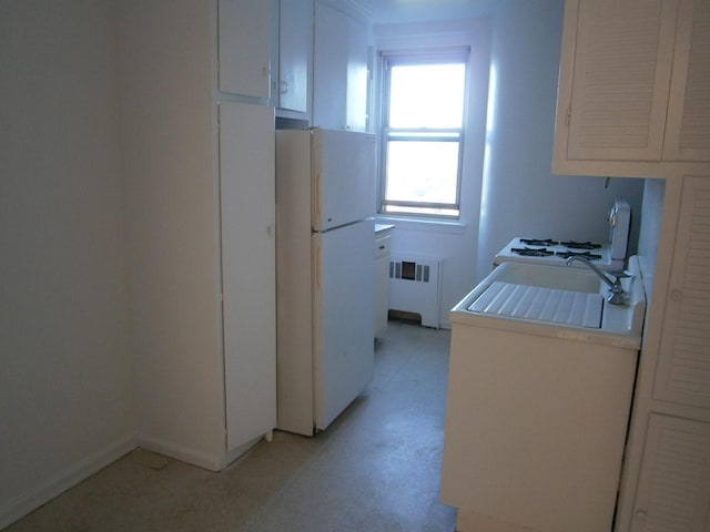 kitchen featuring light countertops, white cabinetry, freestanding refrigerator, and radiator