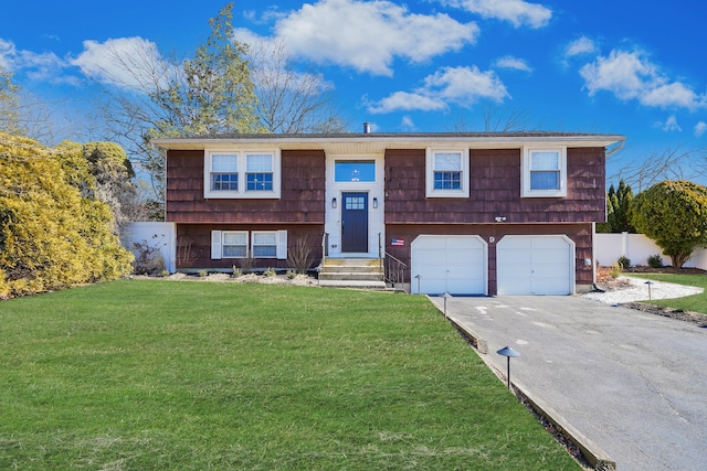 bi-level home featuring a garage, driveway, a front lawn, and fence