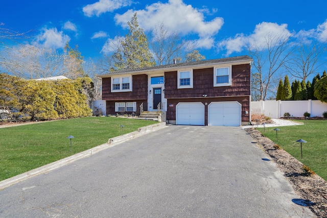 raised ranch with an attached garage, aphalt driveway, a front yard, and fence