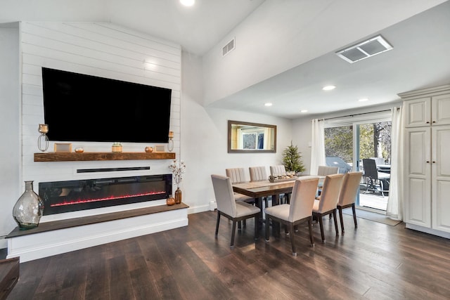 dining space with dark wood-style flooring, a glass covered fireplace, visible vents, and baseboards