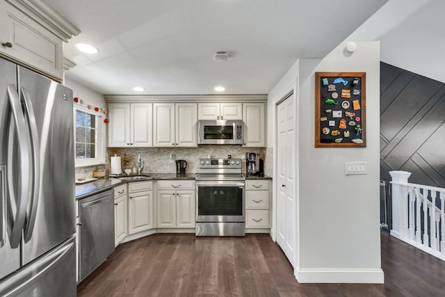 kitchen featuring stainless steel appliances, dark countertops, dark wood-type flooring, and decorative backsplash